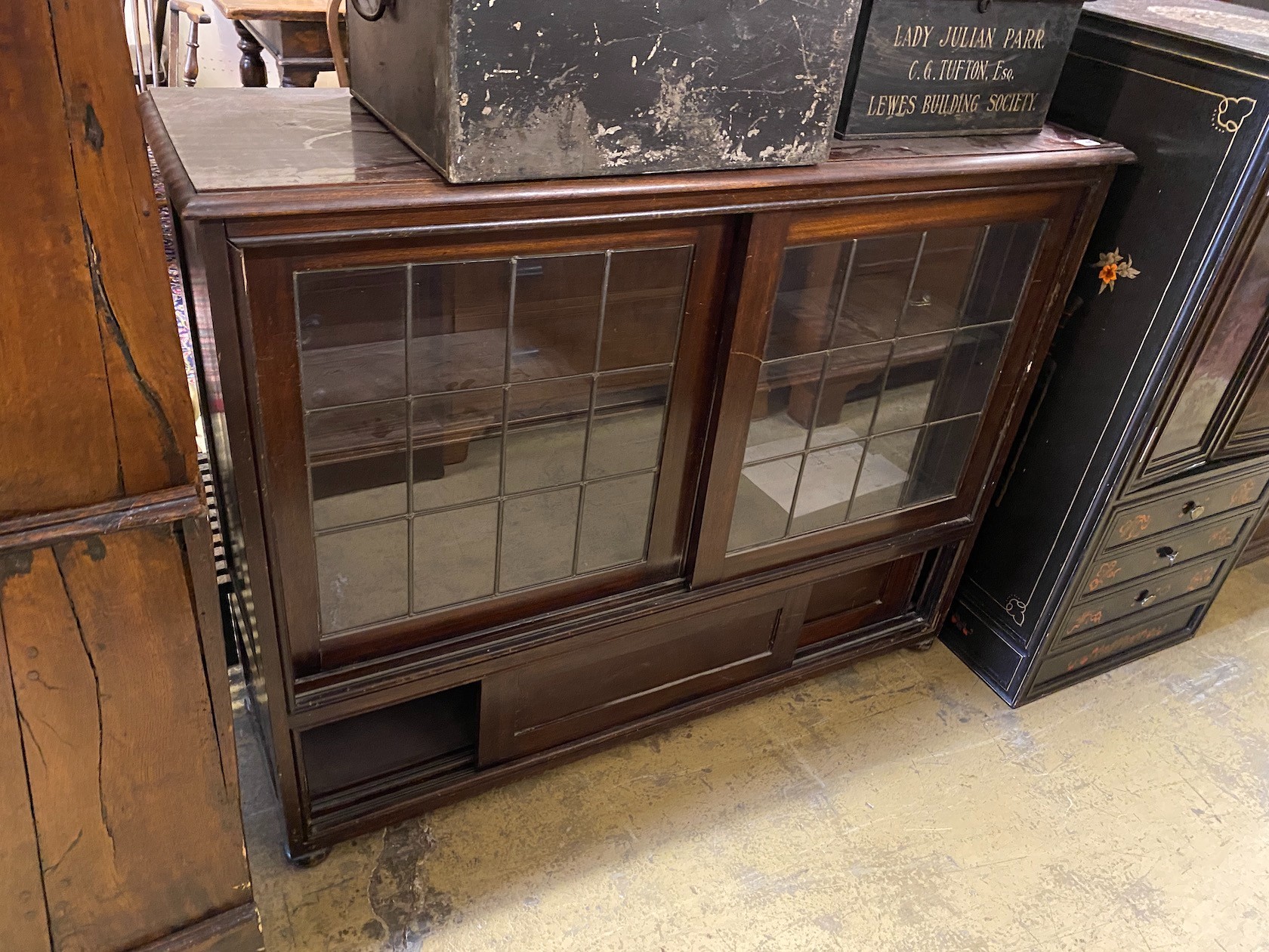 An early 20th century mahogany bookcase enclosed by two sliding leaded glazed doors, length 124cm, width 38cm, height 97cm